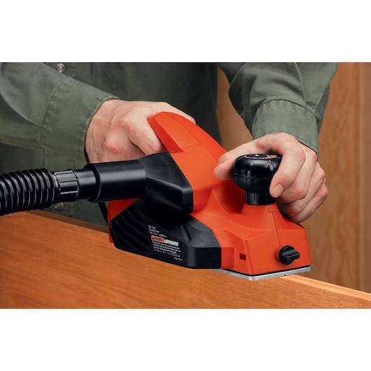Photo of BLACKDECKER 7698K electric hand planer in use on wood edge, shown with black hose attachment.