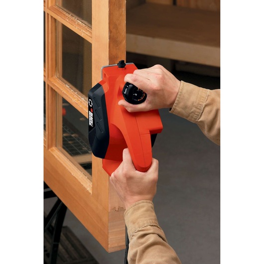 BLACKDECKER 7698K orange and black hand planer in use, smoothing wooden door edge.