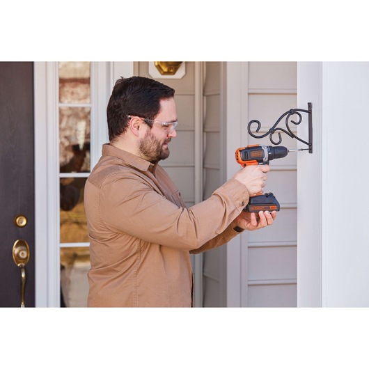 BLACKDECKER BCD703C1 cordless drill used to install a metal wall bracket outdoors.