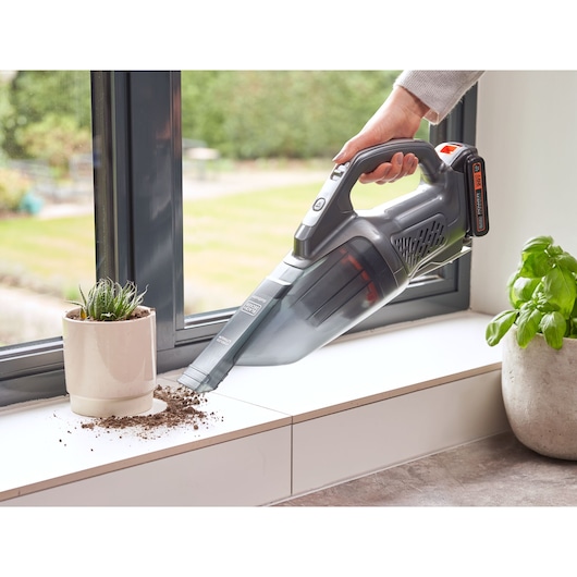 Photo of BLACKDECKER BCHV001D1 handheld vacuum cleaner used to clean spilled soil near window plants.