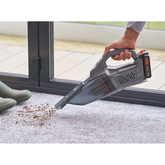 BLACKDECKER BCHV001D1 handheld vacuum cleaning dirt from a light carpet near a door.