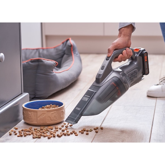 BLACKDECKER BCHV001D1 handheld vacuum cleaning spilled pet food near a bowl and pet bed indoors.