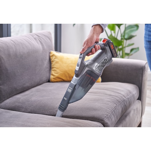 BLACKDECKER BCHV001D1 handheld vacuum cleaner with gray finish cleaning a sofa, home interior background.
