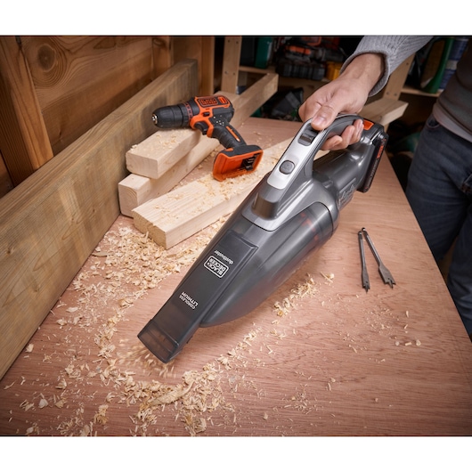 BLACK+DECKER BCHV001D1 handheld vacuum cleaning wood shavings on workbench, drill and wood pieces visible, front angle.