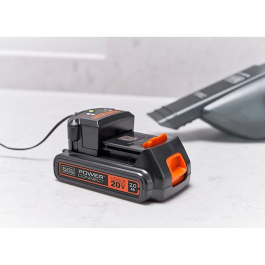 BLACKDECKER BCHV001D1 20V lithium battery on charger, tabletop angle, black and orange design.