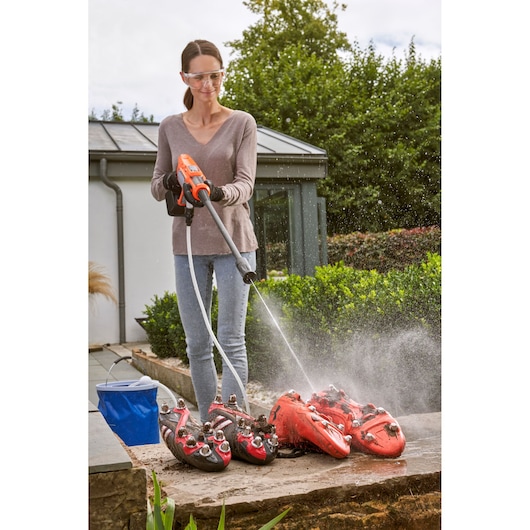 Photo of person using BLACKDECKER BCPC20D1 cordless power washer to clean red sports shoes outdoors.