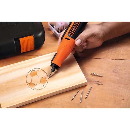 BLACK+DECKER BCRT8K35 rotary tool engraving a soccer ball design on wood, kit and accessories visible.
