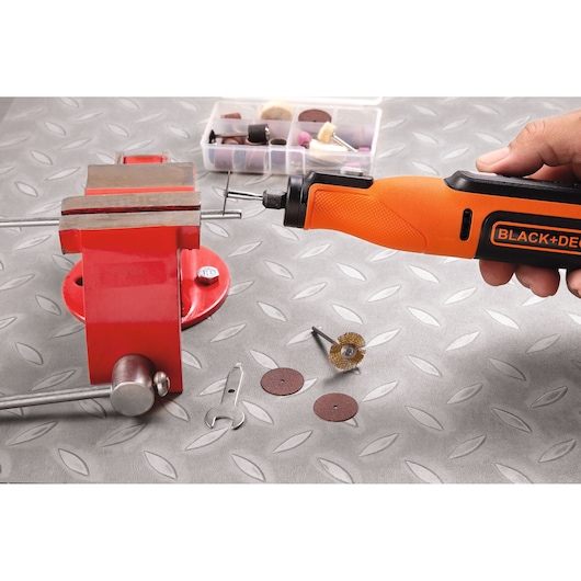 BLACK+DECKER BCRT8K35 rotary tool set with orange handle, metal vise, and accessories on a patterned surface.