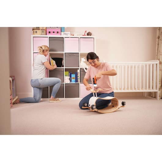BLACKDECKER BCRTA601I cordless screwdriver used to assemble wooden toy in nursery, shelving visible.