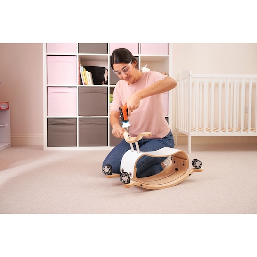 BLACKDECKER BCRTA601I tool used to assemble wooden ride-on toy in a nursery setting.