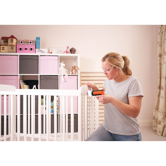 BLACKDECKER BCRTA601I cordless screwdriver used on white crib in nursery with storage shelves.