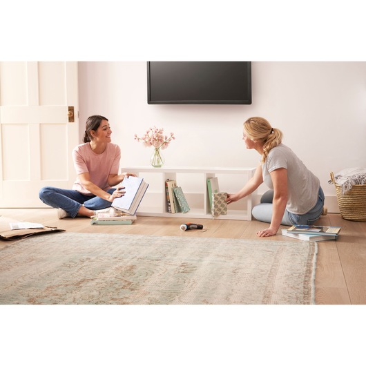 BLACKDECKER BCRTA601I cordless screwdriver on floor with two women organizing books in a living room.