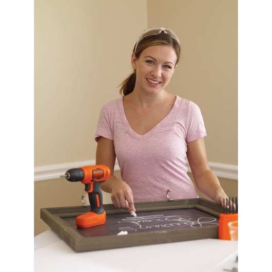 Photo of BLACKDECKER BDCD8C cordless drill in orange and black on a chalkboard frame with accessories.
