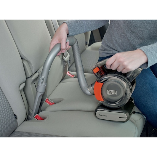 Photo of BLACK+DECKER BDCV560F-LA handheld vacuum cleaner being used to clean a car seat, flexible hose attached.