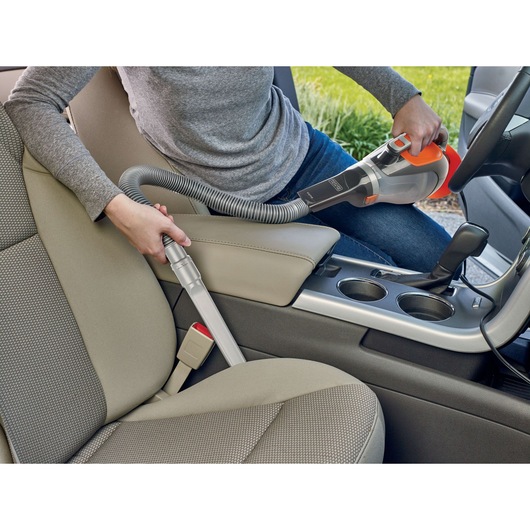 BLACKDECKER BDCV610-LA handheld vacuum cleaning car seat area with flexible hose attachment.
