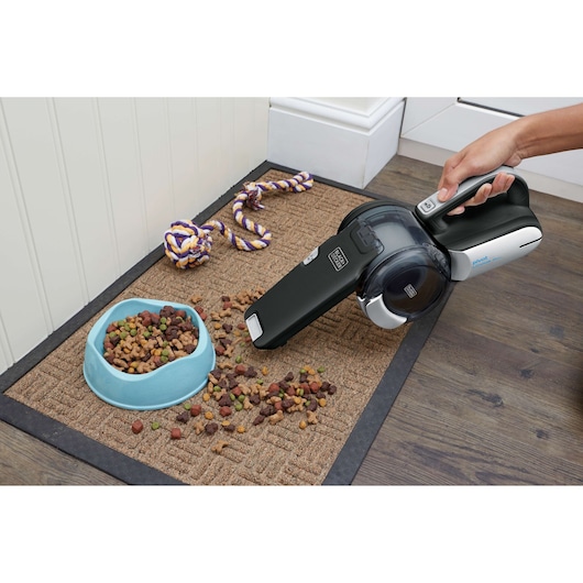 BLACKDECKER BDH2000PL handheld vacuum cleaning spilled pet food from mat, close-up photography.