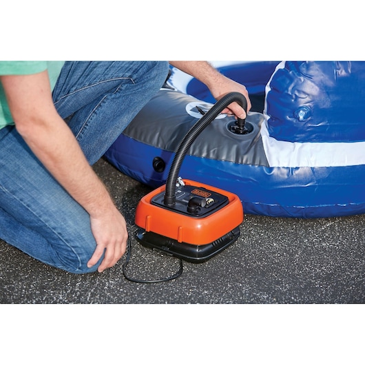 BLACKDECKER BDINF12C portable inflator in use inflating a blue and gray pool float outdoors.