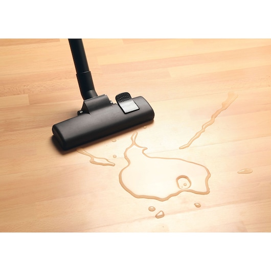 BLACKDECKER BDWD10 vacuum cleaner head on wooden floor absorbing water spill, close-up angle.