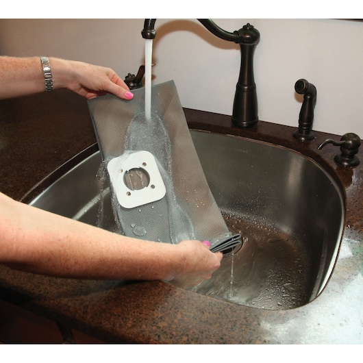 BLACKDECKER BDWD10 vacuum filter being washed under tap water in a kitchen sink.