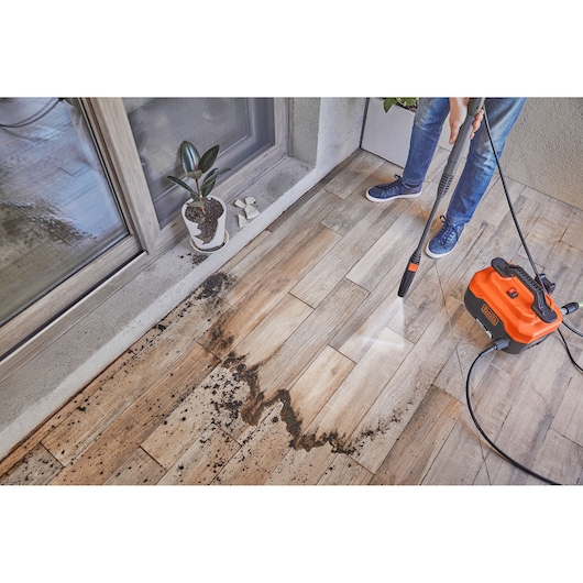 BLACKDECKER BEPW1600H pressure washer cleaning dirty tile floor, photo shows water spray removing soil.