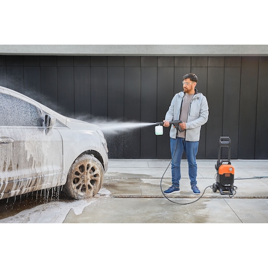 BLACKDECKER BEPW2200 pressure washer spraying foam on a car during cleaning, outdoor use.