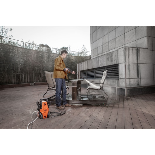 BLACKDECKER BEPWB1740 pressure washer used outdoors to clean patio chairs and table, product visible in foreground.