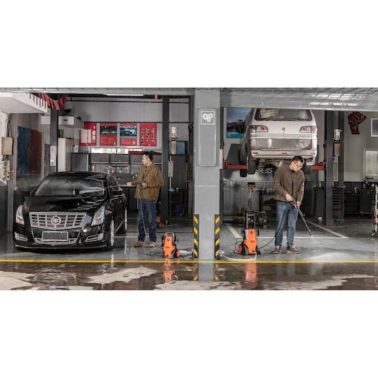 BLACKDECKER BEPWB2000 pressure washer in use at a car workshop, two people cleaning cars.