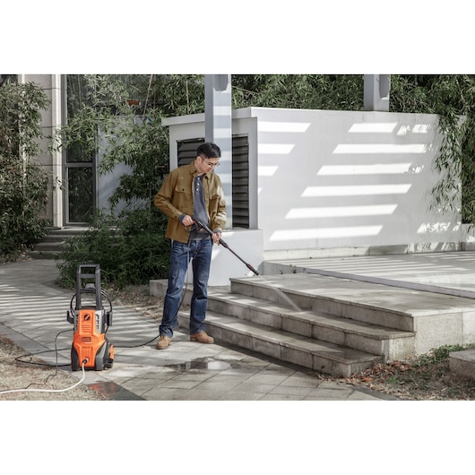 BLACKDECKER BEPWB2000 pressure washer cleaning outdoor stairs, orange unit on pavement.