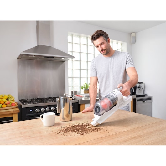 BLACKDECKER BHFEA520J cordless handheld vacuum cleaning coffee grounds on kitchen counter.
