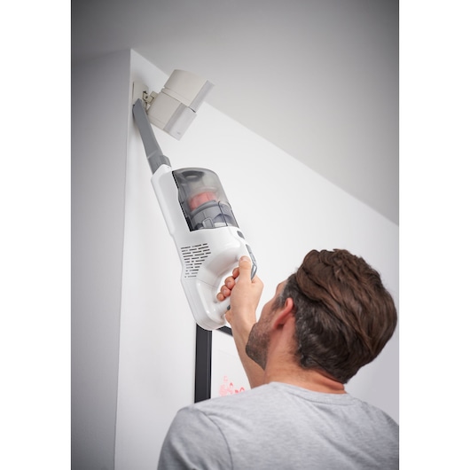BLACKDECKER BHFEA520J cordless stick vacuum with extension tube cleaning ceiling corner.
