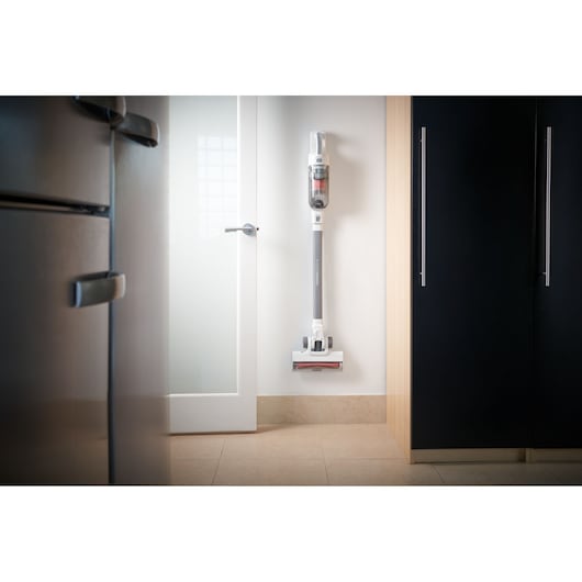 BLACKDECKER BHFEA520J cordless stick vacuum mounted on kitchen wall between cabinets and door.