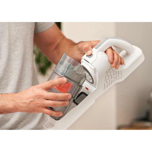 Photo of a BLACKDECKER BHFEA520J cordless vacuum cleaner with a person removing the dust container.