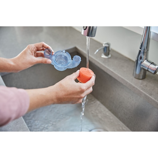 BLACKDECKER BHSB320JP sponge being rinsed under faucet in kitchen sink, close-up photography.