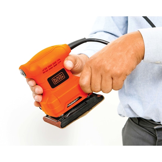 Photo of BLACKDECKER BS200 orange electric sander held in hand, close-up against white background.