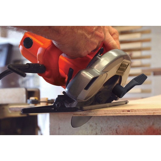 BLACKDECKER CS1004 circular saw cutting wood, close-up of blade and handle in workshop setting.