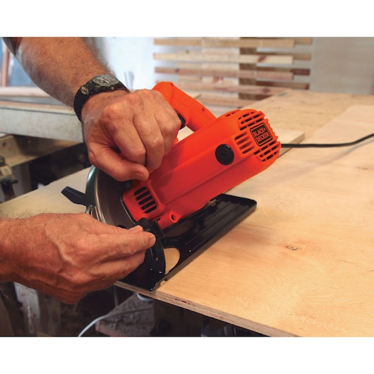 BLACKDECKER CS1004 circular saw being adjusted on plywood in a workshop setting.