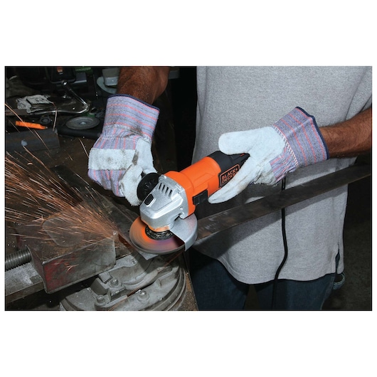 BLACKDECKER G650 angle grinder in use, worker wearing gloves cutting metal, visible sparks.