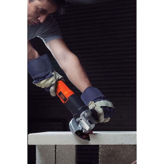 BLACKDECKER G720 angle grinder cutting stone block, operator wearing protective gloves.
