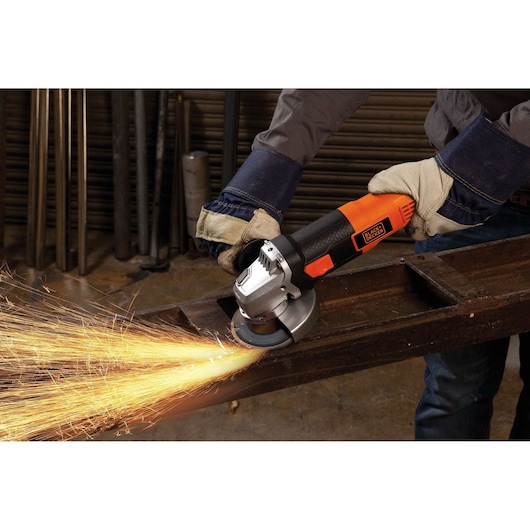 Photo of BLACKDECKER G720 angle grinder in use, grinding metal and producing sparks, held by gloved hands.