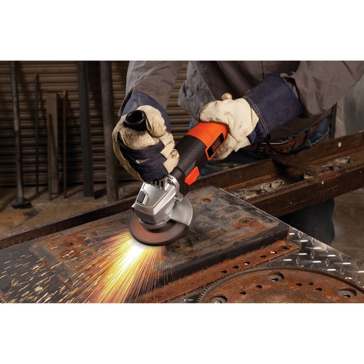 BLACKDECKER G720 angle grinder in use, producing sparks on a rusty metal surface, worker wearing gloves.
