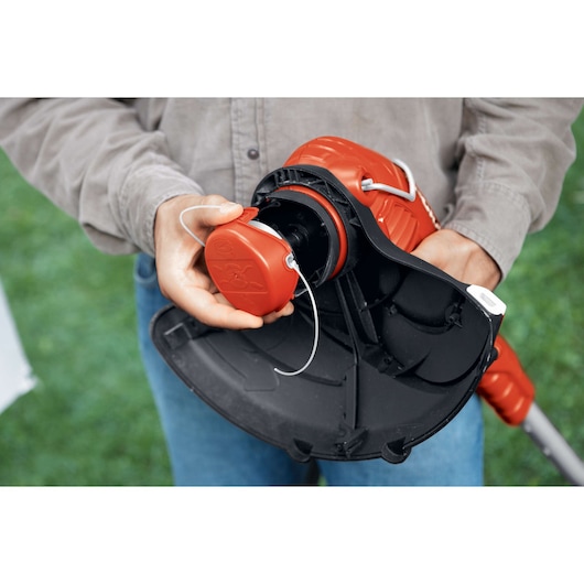 BLACKDECKER GH750 string trimmer being serviced, close-up of spool housing outdoors.