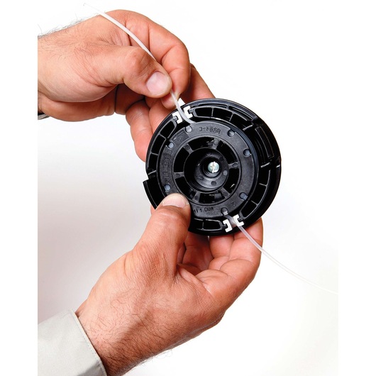 BLACKDECKER GST26 trimmer spool with line held in hands, close-up, white background.