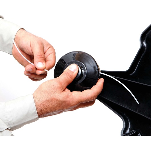 Photo of hands loading line into BLACKDECKER GST26 grass trimmer head, close-up on white background.