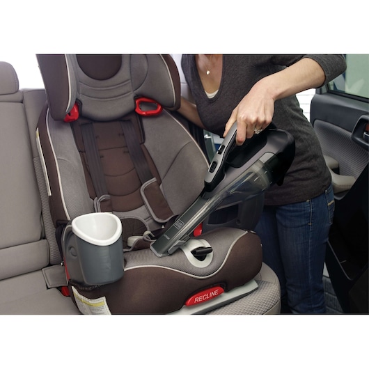 BLACKDECKER HLVA320J00 handheld vacuum cleaning a child car seat in a vehicle interior.