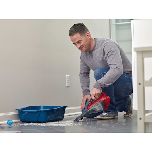 BLACKDECKER HLVA320J26 handheld vacuum cleaning floor near blue litter box.