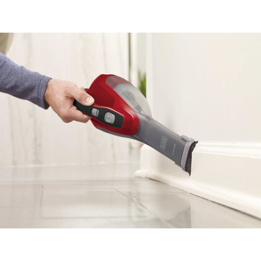 Photo of BLACKDECKER HLVA320J26 handheld vacuum in red and gray cleaning floor molding.