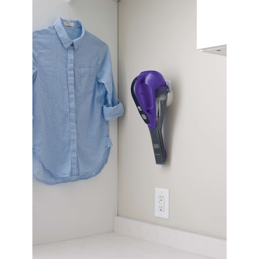 BLACKDECKER HLVA325JP07 handheld vacuum in purple mounted on wall near blue shirt.