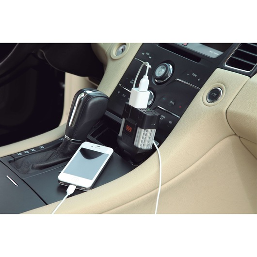 BLACKDECKER PI100LA power inverter plugged in car console, charging smartphone via USB cable.