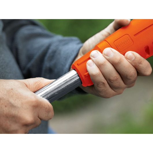 Close-up photo of hands assembling the orange BLACK+DECKER ST4500 trimmer handle outdoors.