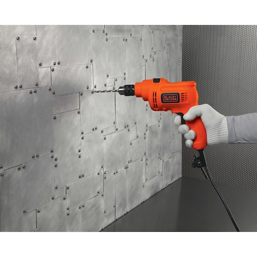 Photo of BLACKDECKER TP550 orange electric drill used on a metal wall, side angle.